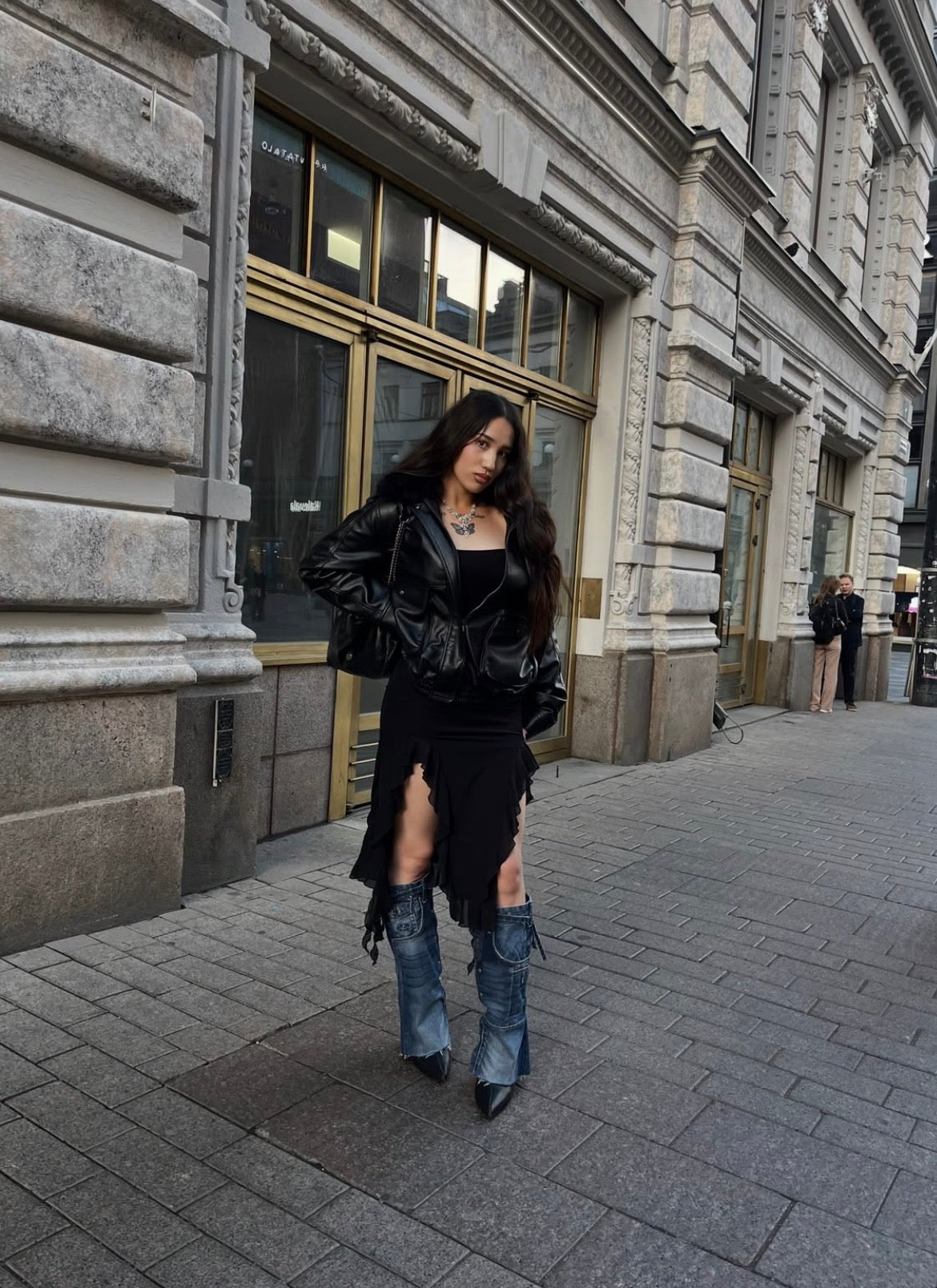 Helmi wearing Denim Heights blue denim boots with a black outfit on a city street